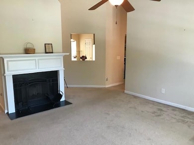 Living room with carpet flooring, a ceiling fan, baseboards, and a fireplace with flush hearth