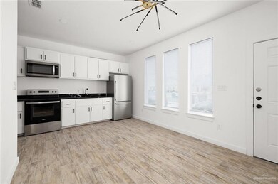 Kitchen with stainless steel appliances, light wood-style floors, dark countertops, and white cabinets