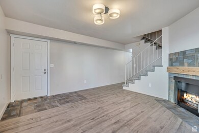 Unfurnished living room with wood finished floors, a tile fireplace, and stairway