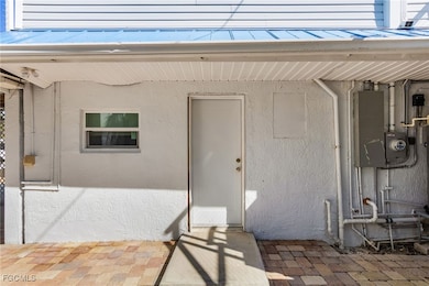 Entrance to property featuring stucco siding, a patio area, a metal roof, and electric panel