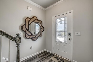 Entrance foyer with dark wood-type flooring, crown molding, and baseboards