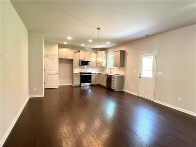 Kitchen with appliances with stainless steel finishes, light countertops, dark wood-type flooring, recessed lighting, and hanging light fixtures
