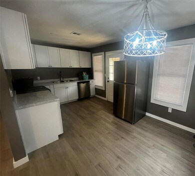 Kitchen with sink, white cabinetry, wood-type floo
