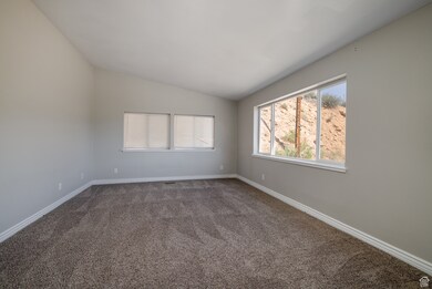 Carpeted empty room with lofted ceiling and baseboards