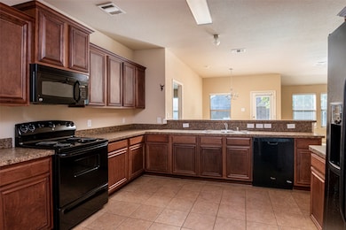 Kitchen with black appliances, light tile patterned floors, a chandelier, healthy amount of natural light, and a textured ceiling