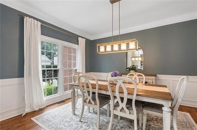 Dining space with crown molding, and a wainscoted wall