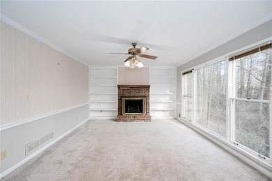 Unfurnished living room with ceiling fan, crown molding, carpet flooring, baseboards, and a fireplace
