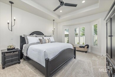 Bedroom featuring light carpet, a tray ceiling, recessed lighting, and a ceiling fan