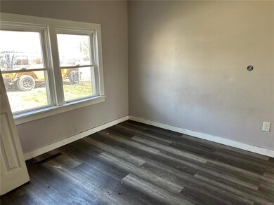 Empty room featuring visible vents, dark wood-type flooring, and baseboards