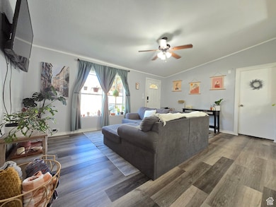 Living room with crown molding, wood finished floors, and ceiling fan