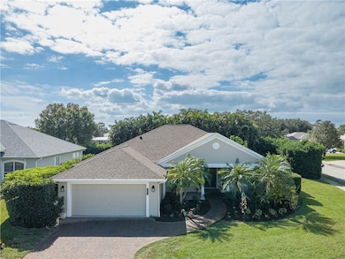 Single story home featuring a shingled roof, a front lawn, driveway, and stucco siding