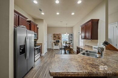 Kitchen with kitchen peninsula, dark hardwood / wood-style floors, appliances with stainless steel finishes, decorative light fixtures, and sink