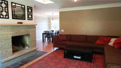 Large Living Room with wood burning fire place, neutral wall color, and beautiful hardwood floors.