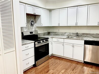 Kitchen with stainless steel appliances, white cabinetry, and light wood-style floors