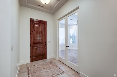 Foyer entrance with light tile patterned flooring, french doors, and inlaid floor details