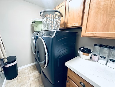 Laundry area featuring washer and clothes dryer, light tile patterned flooring, and cabinet space