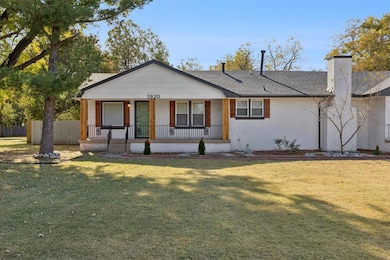 View of front facade with brick siding, a porch, a chimney, and a shingled roof