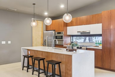 The kitchen is a masterpiece of form and function, featuring sleek quartz countertops with a waterfall edge on the oversized central island.