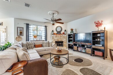 Living room featuring light wood-type flooring, a stone fireplace, and ceiling fan