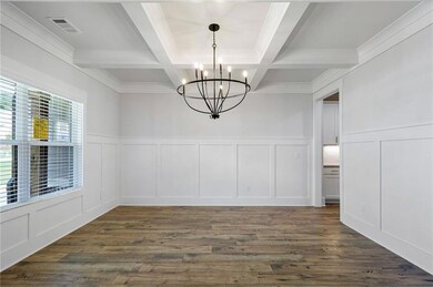 Unfurnished dining area featuring beam ceiling, a decorative wall, dark wood finished floors, a chandelier, and wainscoting