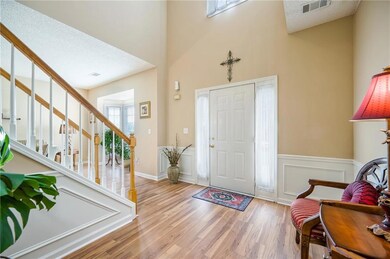 Foyer entrance with wood finished floors, stairway, wainscoting, a high ceiling, and a textured ceiling