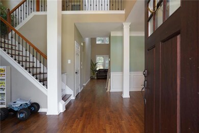 Entryway featuring a towering ceiling, decorative columns, dark wood-style flooring, stairs, and wainscoting