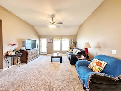 Living area featuring lofted ceiling, ceiling fan, and carpet