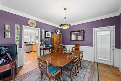 Dining room featuring crown molding, light wood-style flooring, wainscoting, and a chandelier
