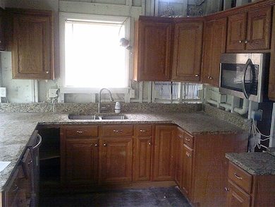 Kitchen featuring stainless steel microwave, a peninsula, brown cabinets, and a sink