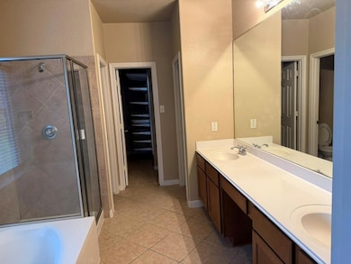 Bathroom featuring a shower stall, double vanity,