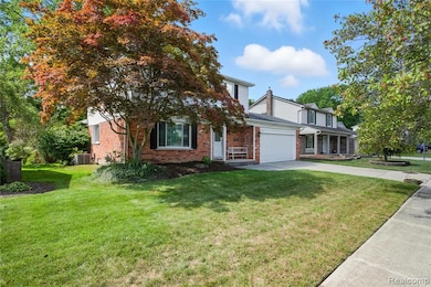 View of front of home with brick siding, concrete driveway, a front yard, an attached garage, and a porch