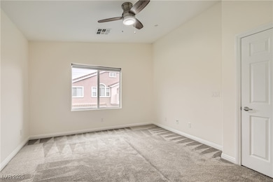 Carpeted spare room with a ceiling fan, baseboards