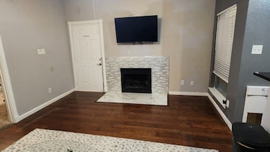 Entry into the living room with a tile fireplace and wood finished floors