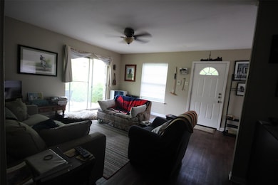 Living room featuring ceiling fan and dark wood-s