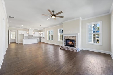 Unfurnished living room with crown molding, dark wood-style flooring, a fireplace, and plenty of natural light