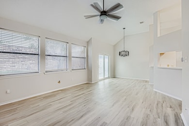 Unfurnished living room featuring light wood-style flooring, ceiling fan, high vaulted ceiling, and a chandelier