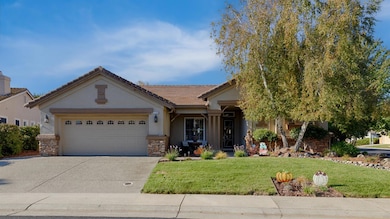 view of front of home featuring a front lawn, an attached garage, stone siding, driveway, and stucco siding