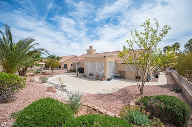 Rear view of property with a patio, stucco siding, a chimney, a fenced backyard, and a tiled roof