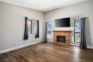 Unfurnished living room featuring wood finished floors and a brick fireplace