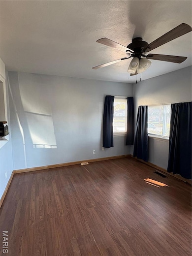Spare room featuring dark wood-style floors, ceiling fan, and a textured ceiling