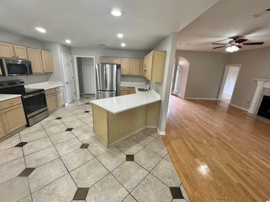 Kitchen with kitchen peninsula, ceiling fan, stain