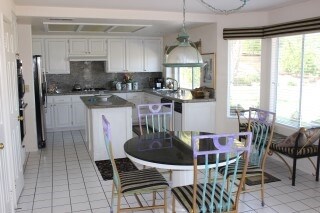 View of the kitchen and dinette area from the family  (all are open to each other). Island and counter tops are granite and there is a pantry next to oven.