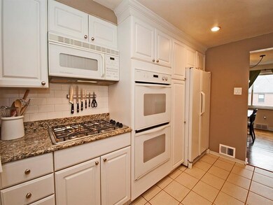 The kichten has white cabinets, granite counters a