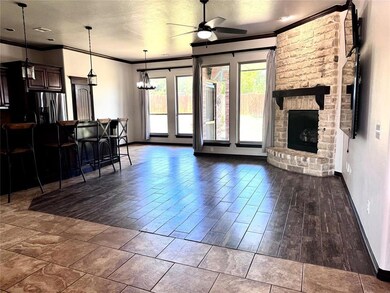 Living room with a ceiling fan, crown molding, baseboards, a stone fireplace, and wood finished floors