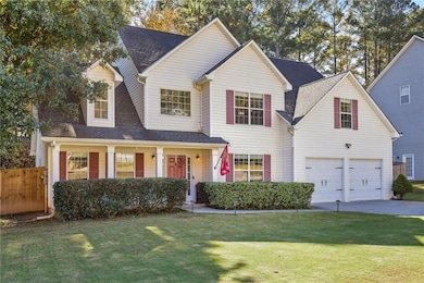 Traditional-style home with roof with shingles, covered porch, an attached garage, and driveway