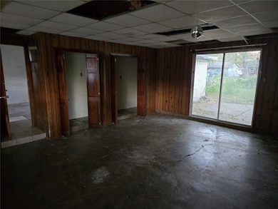 Unfurnished room featuring wooden walls, a paneled ceiling, and unfinished concrete floors