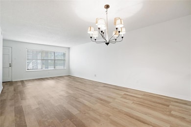 Spare room with an inviting chandelier, a textured ceiling, and light wood-type flooring