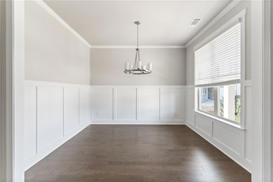 Unfurnished dining area with crown molding, a chandelier, dark wood-style floors, a decorative wall, and visible vents