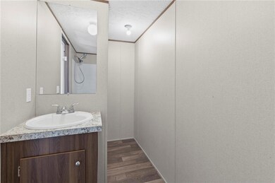 Bathroom with a textured ceiling, dark wood-style flooring, vanity, and crown molding