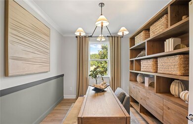 Home office featuring light wood-style flooring, baseboards, and crown molding